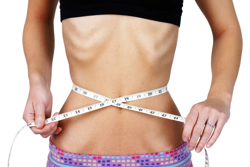 girl with anorexia measuring her waist
