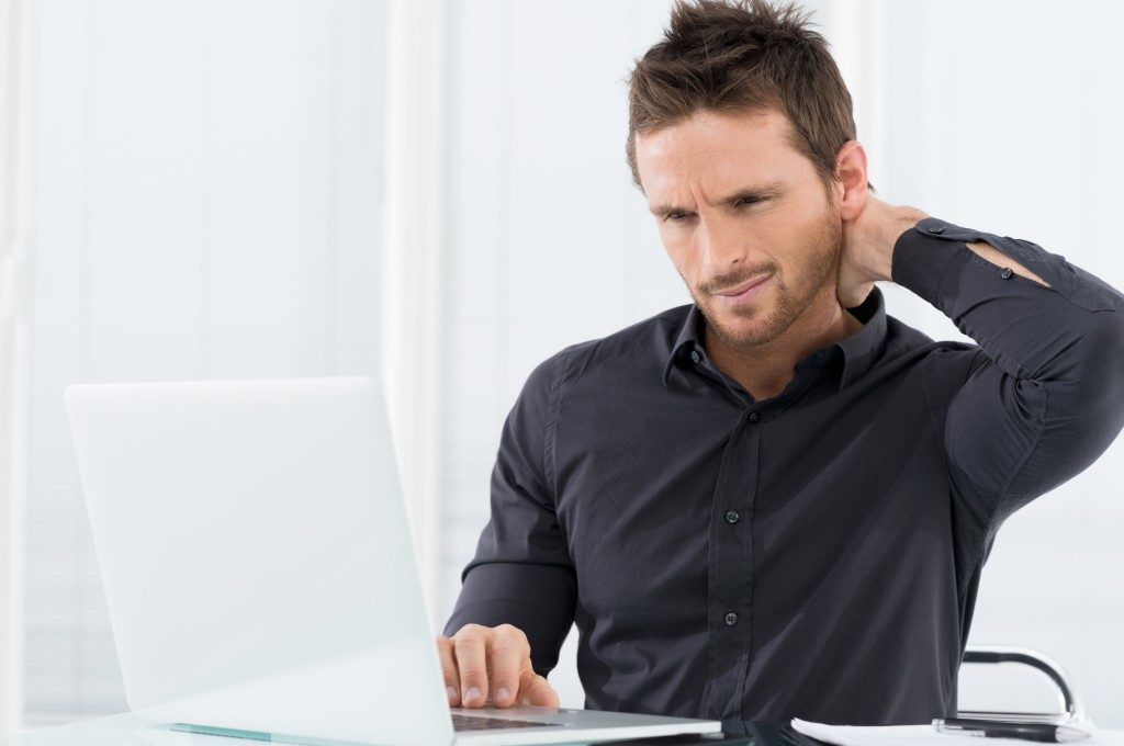 Man experiencing neck pain while at work