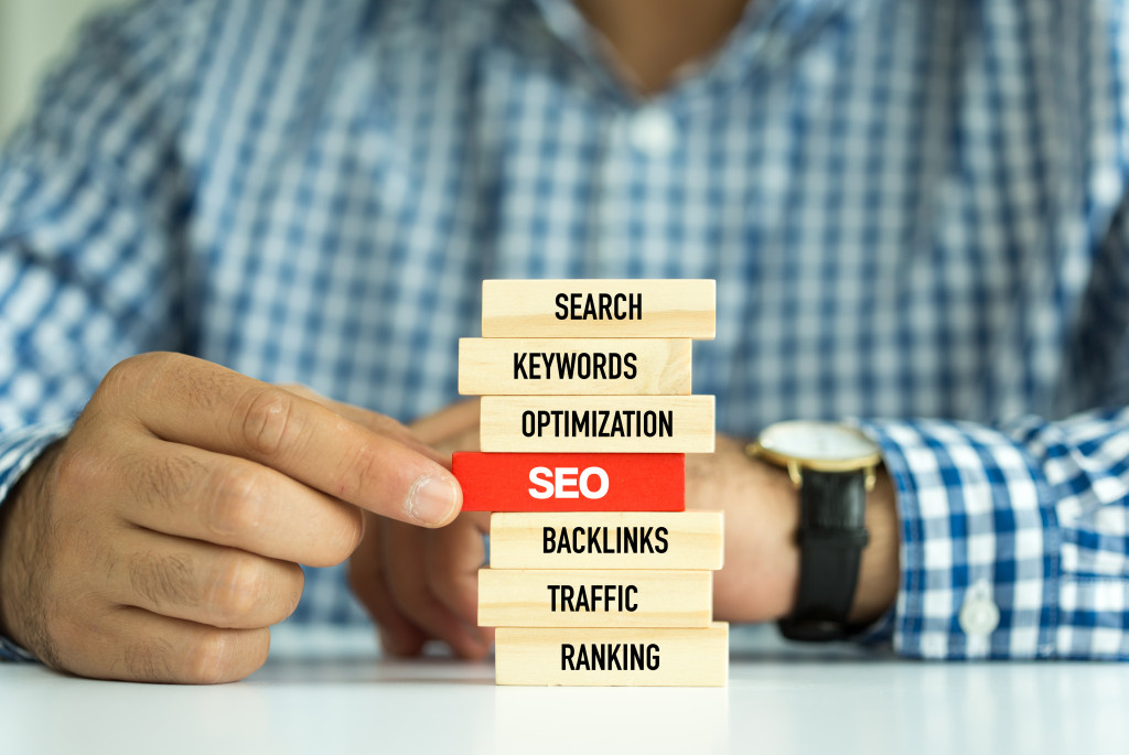 man holding a wooden block that has SEO written on it