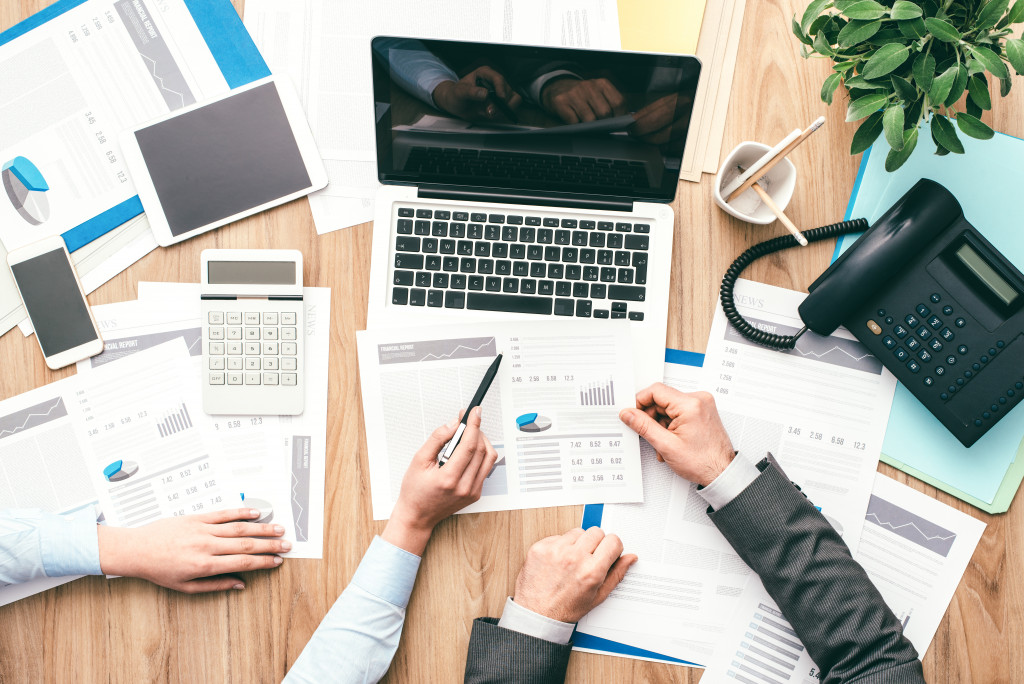 Two men in business look over charts of business expenses