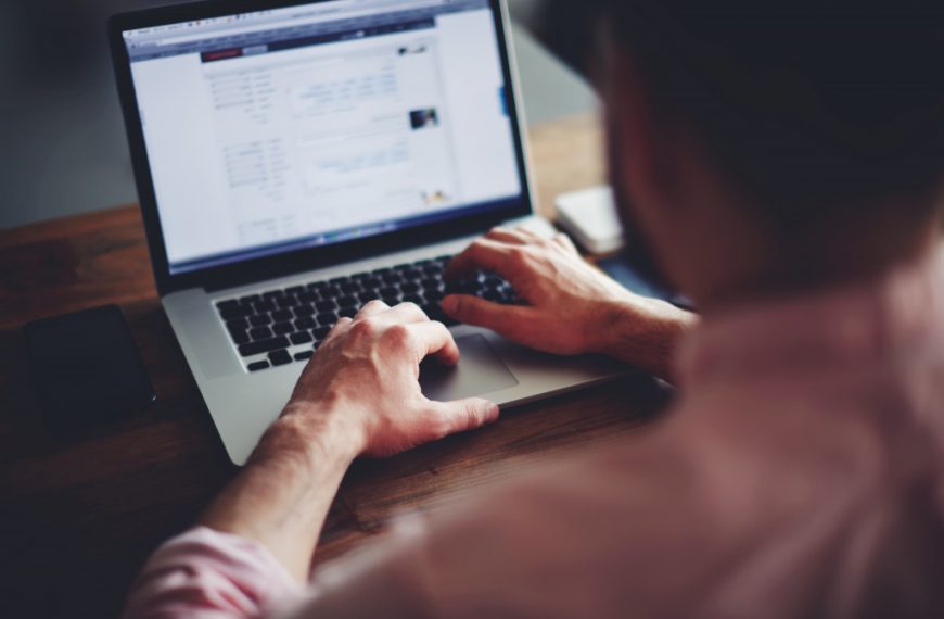 Cropped image of a young man working on his laptop in a coffee shop, rear view of business man hands busy using laptop at office desk, young male student typing on computer sitting at wooden table
