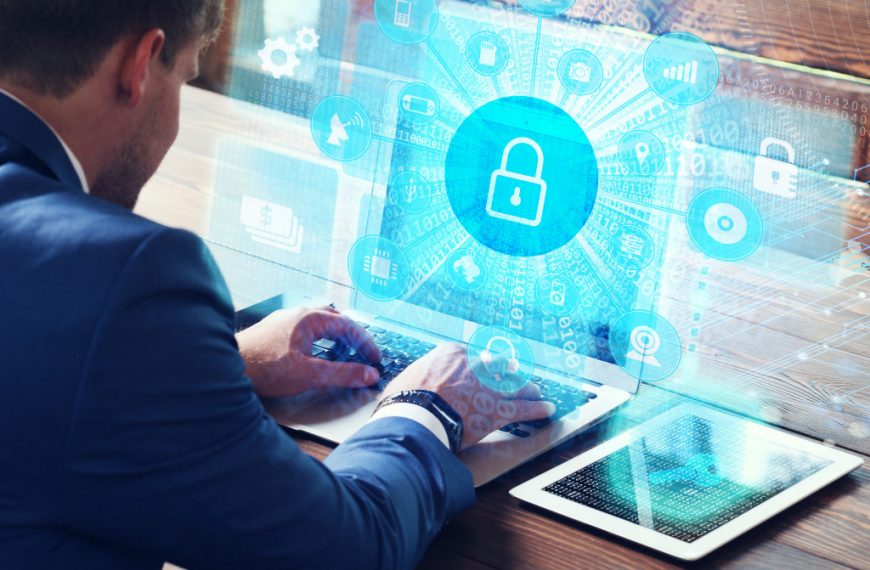 Business, technology, internet and networking concept. Young businessman working on his laptop in the office, select the icon security on the virtual display.