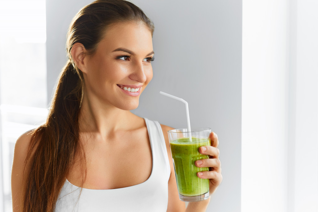 Young woman drinking raw green vegetable detox juice