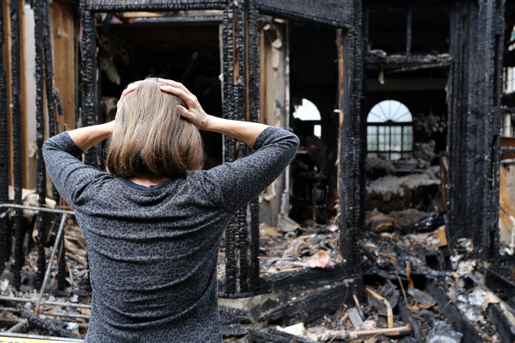 A woman distraught while looking at the aftermath of a fire disaster