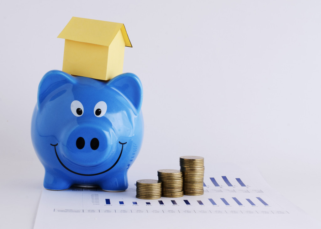 Piggy bank and paper house and coins stack for mortgage loans