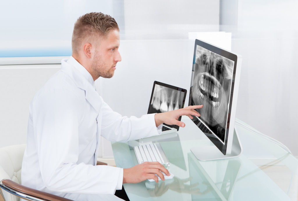 Doctor or radiologist looking at an x-ray online displayed on a desktop monitor as he makes a diagnosis or checks prognosis