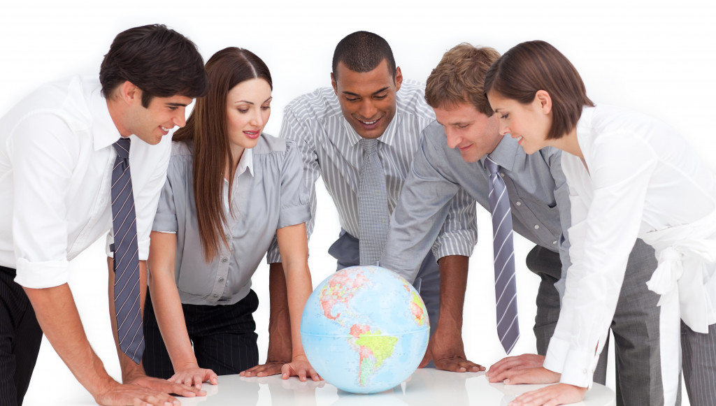 Executives looking at a globe placed on top of a table.