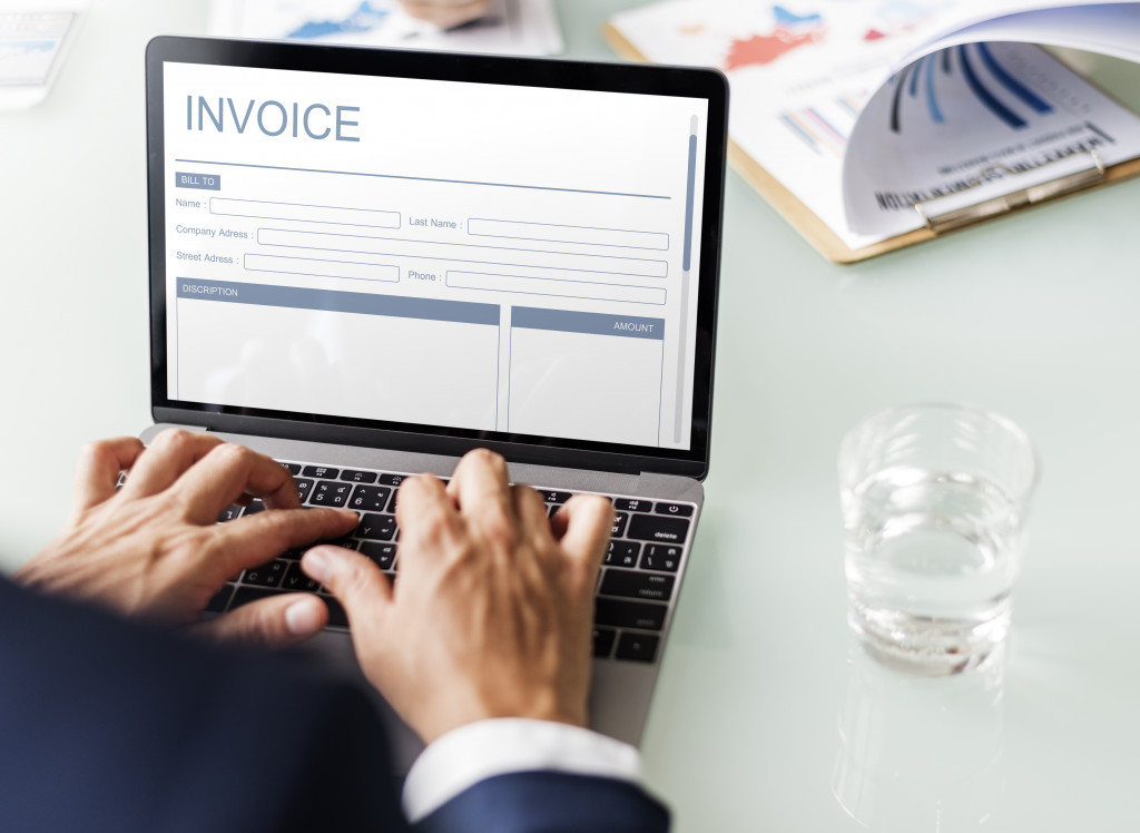 Businessman using laptop software to generate invoice for suppliers 