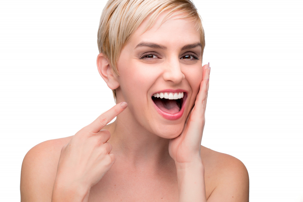 Young short hair blond woman showing her new veneers 