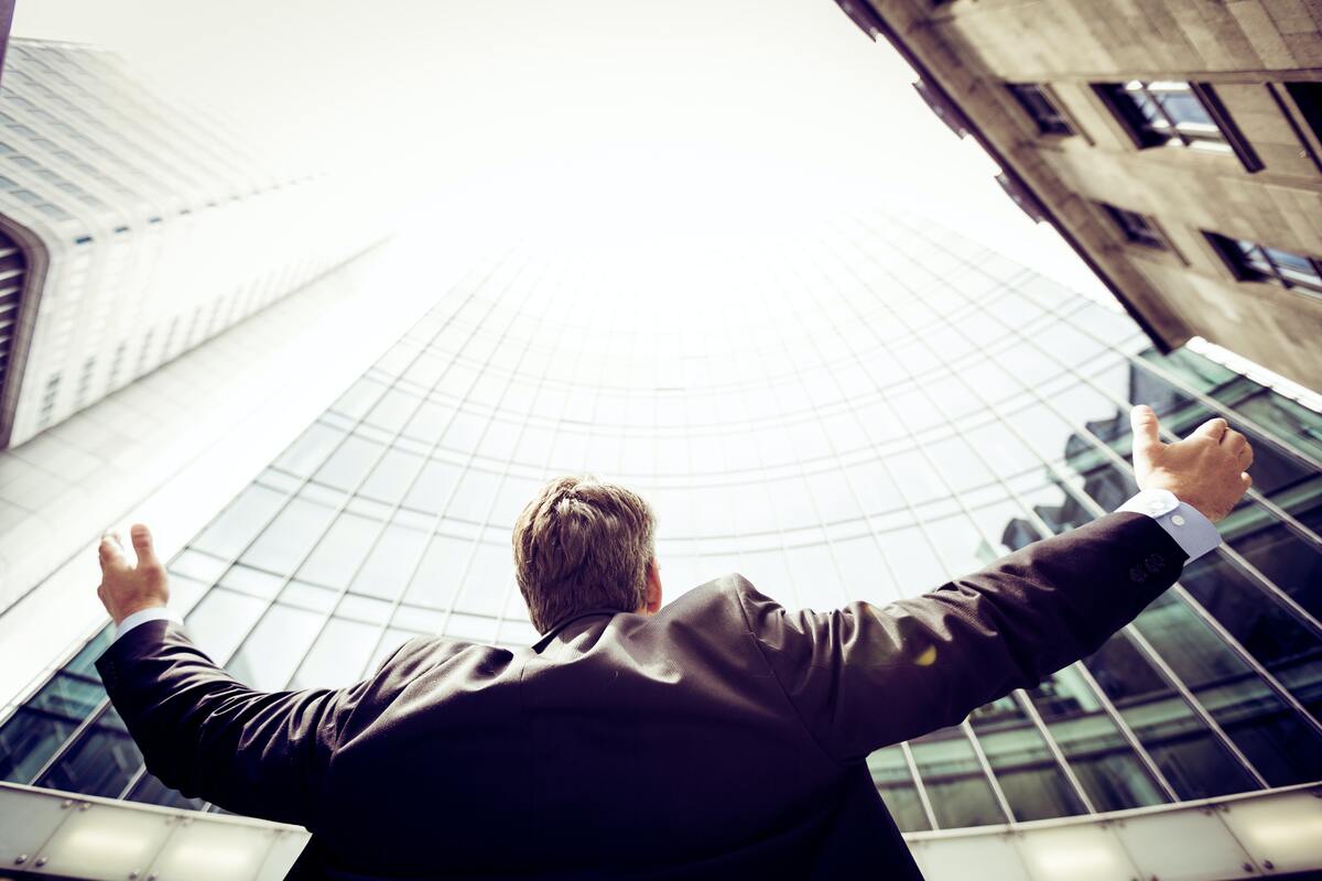 businessman raising his hands in front of commercial buildings