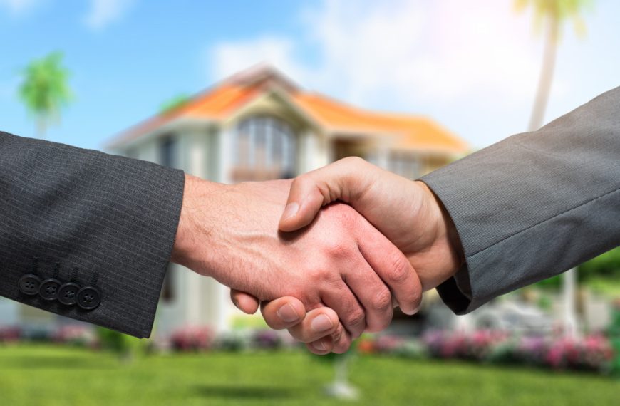 people shaking hands in front of a blurry house