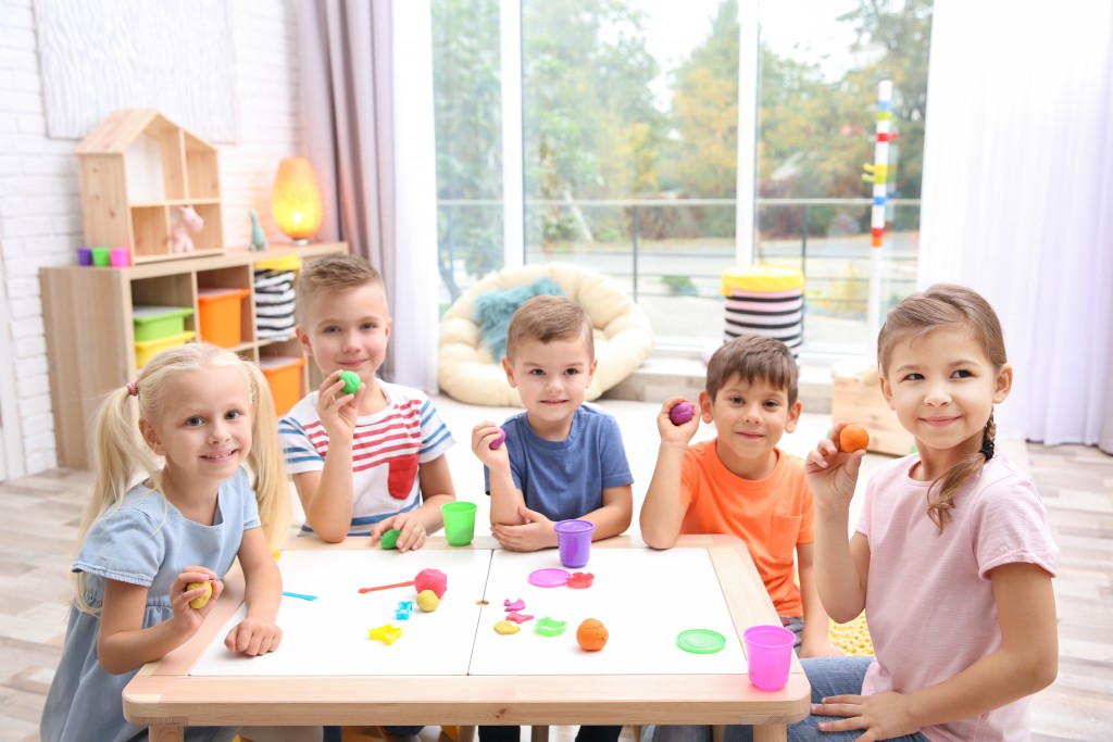 Happy children in a preschool, learning by using clays