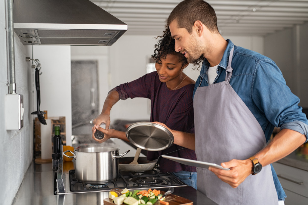 Young couple cooking dinner together in the kitchen of their house.