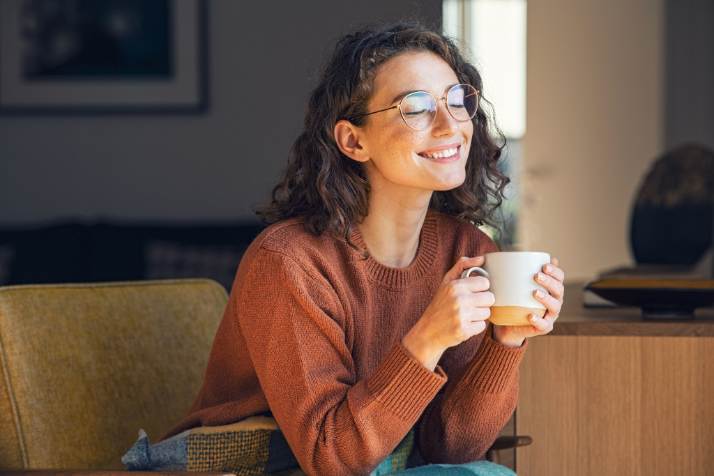 Young woman smiling while enjoying a cup of hot chocolate.