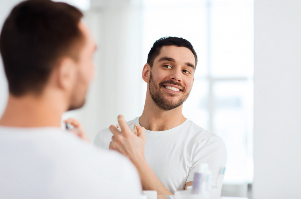 man smiling in the mirror while wearing perfume 