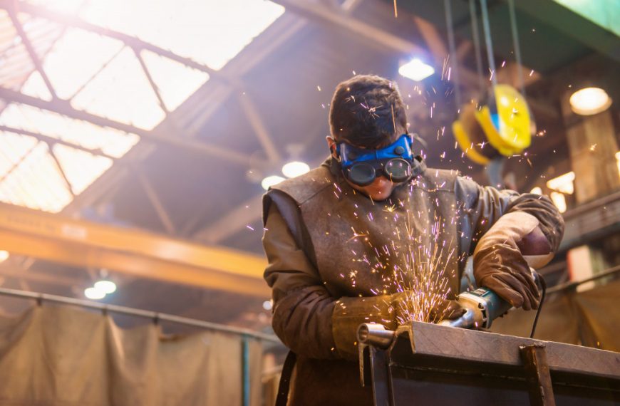 man with protective goggles welding in factory