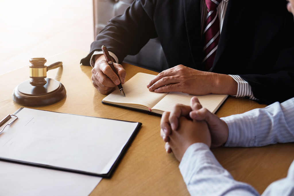 businessman discussing business with lawyer in his office while writing on notebook