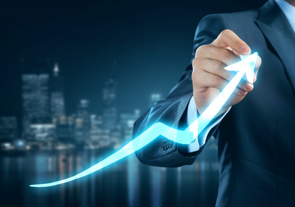 businessman drawing an upward arrow with a marker glowing 