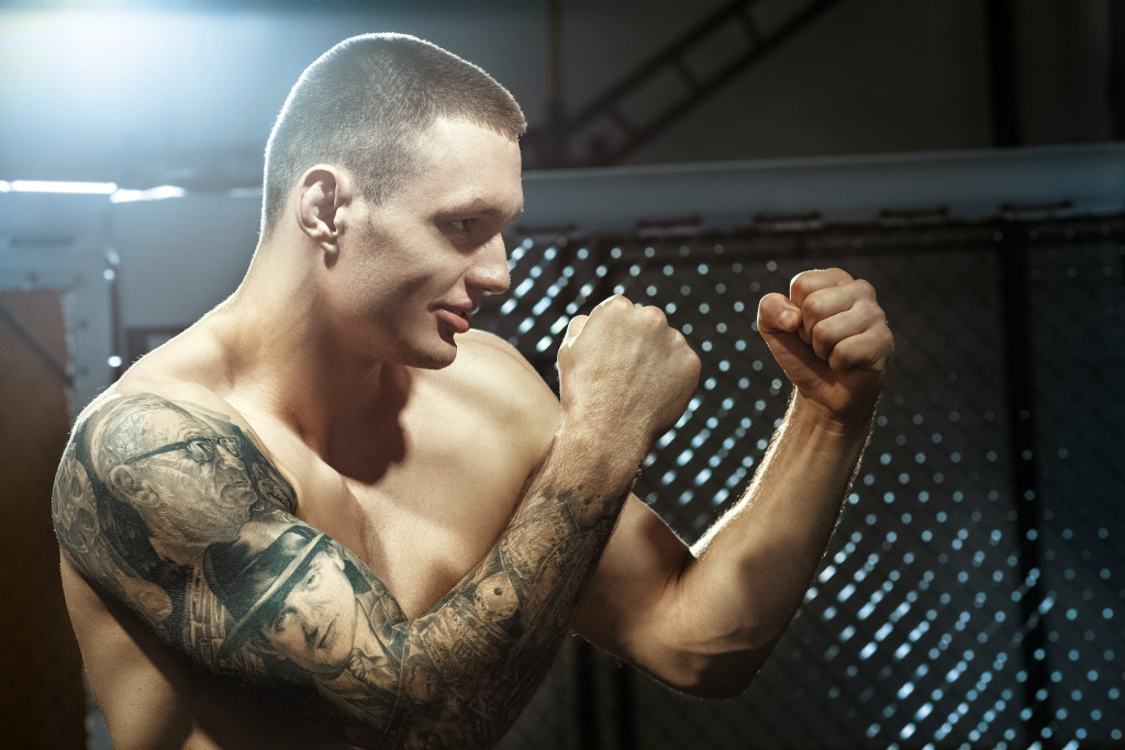 Young male MMA fighter getting ready for a fight in a fighting cage.