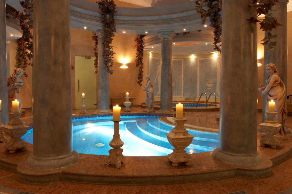 Spa decorated with Roman statues, columns, and candles..