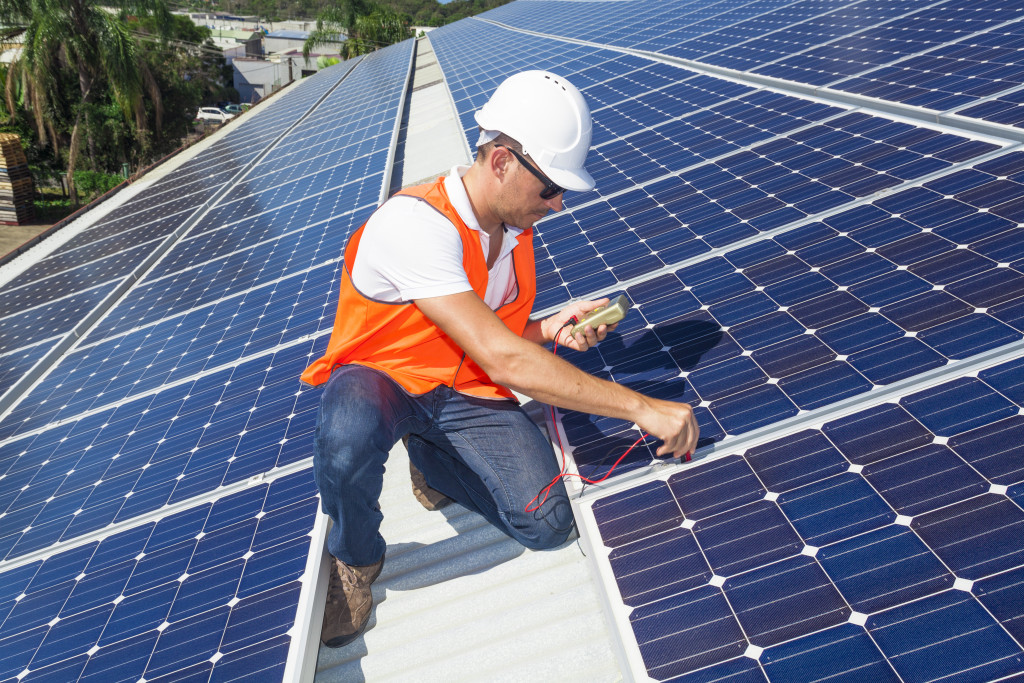Technician checking a solar panel array on the roof of a business.