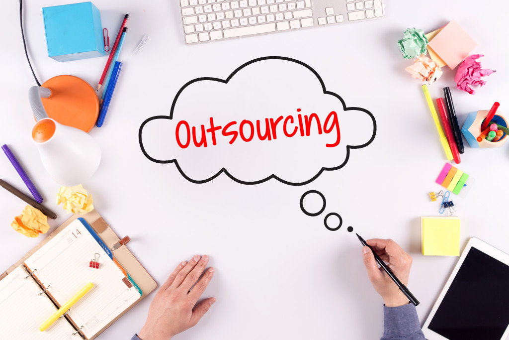 business person writing outsourcing in cloud callout in white office table