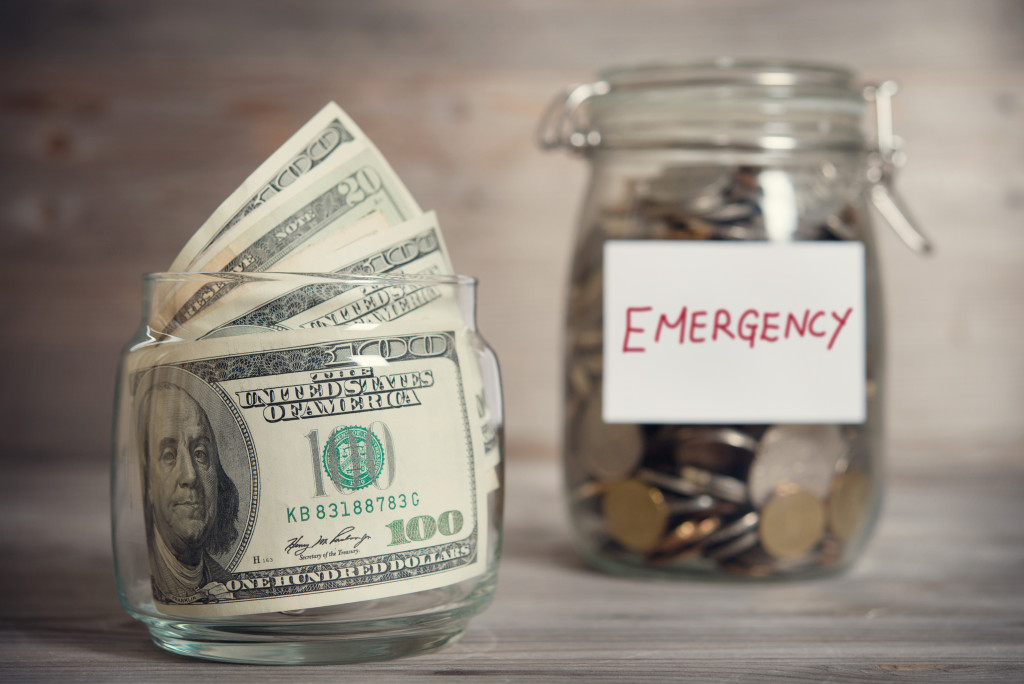 Jars labeled with the word EMERGENCY and filled with coins and bills 
