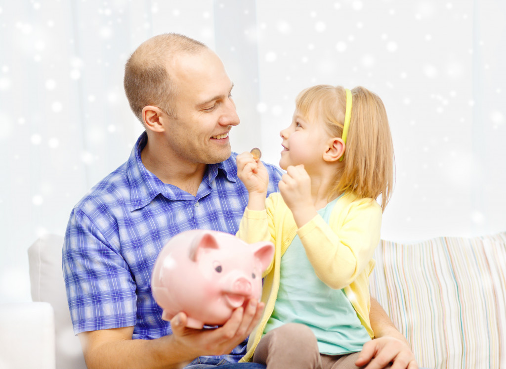 father and daughter putting coins inside a piggy bank
