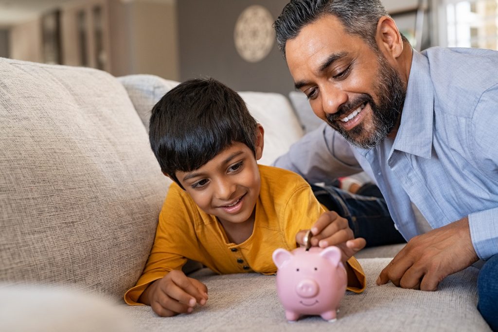 a child saving money in piggy bank with father