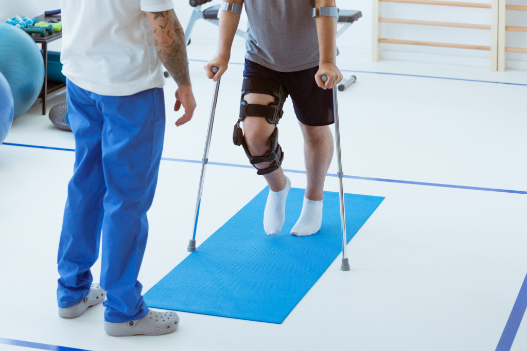 man learning to walk in the clinic, helpful therapist near him