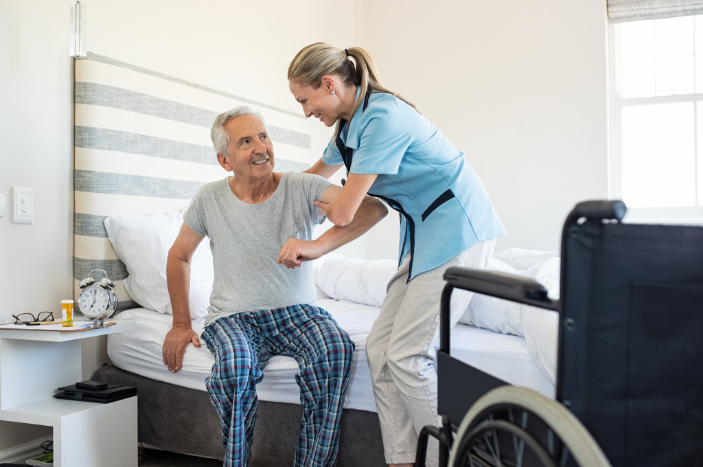 Caring nurse supporting patient while getting up from bed