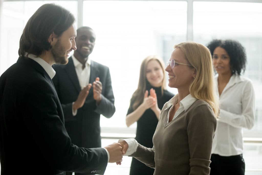 Business executive shaking the hand of a female employee at an office.